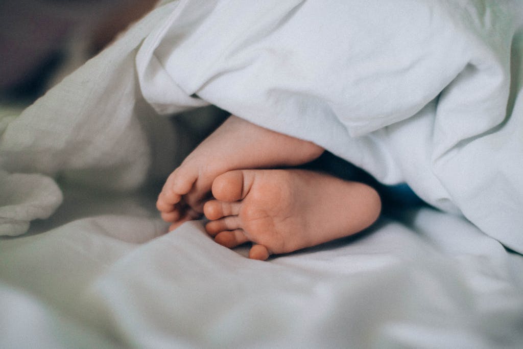 Close-up of tiny baby feet under a blanket, creating a cozy, cute vibe.